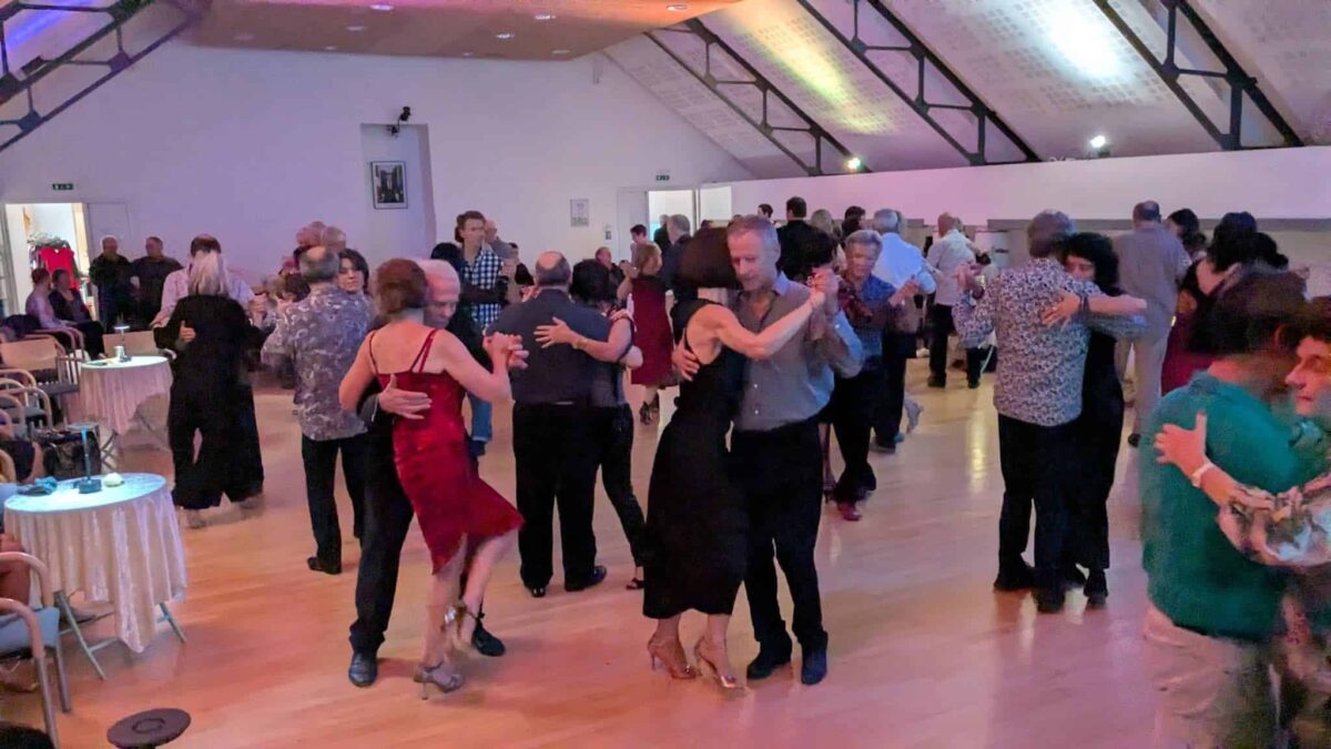 Des couples dansent le tango dans une salle conviviale lors d’une milonga.